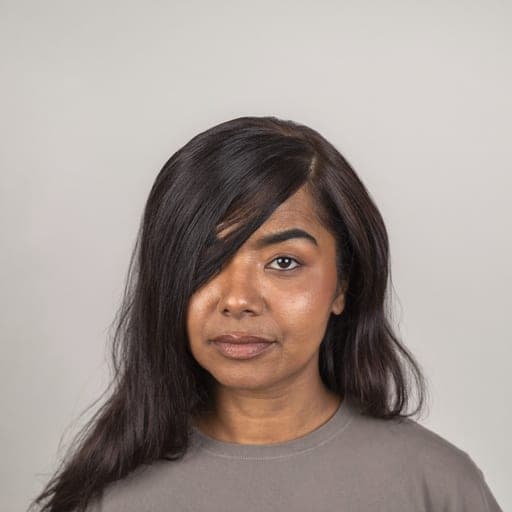 A woman with deep side part: Any length, parted far to one side so the hair falls asymmetrically across the forehead.