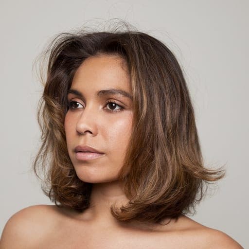 A woman with volume at the crown: Any mid or long cut, dried with lift at the roots so height sits above the forehead.